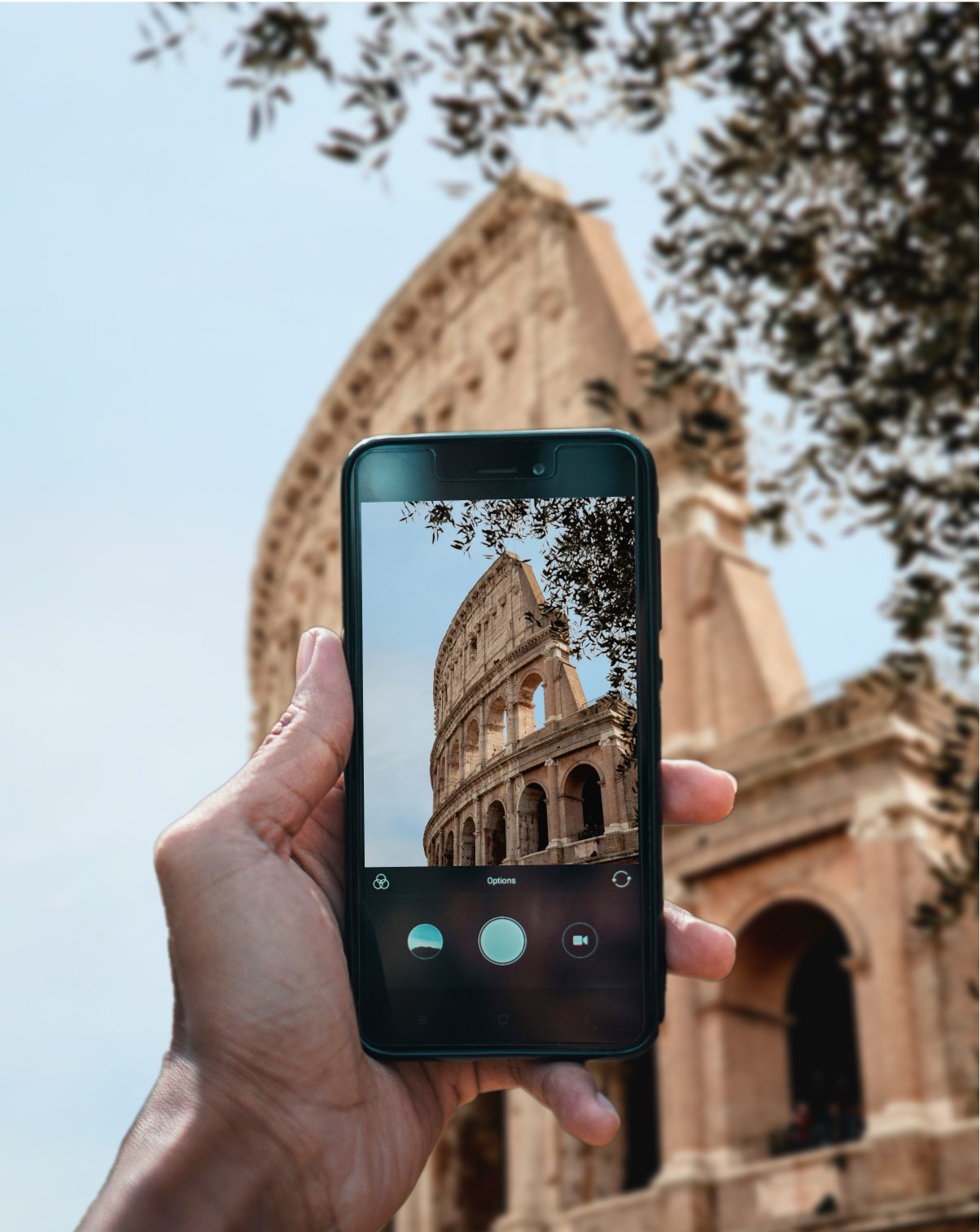 Hand holding a smartphone capturing a photo of the Colosseum in Rome