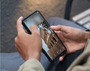 Person holding a smartphone displaying a photo of the Colosseum in Rome