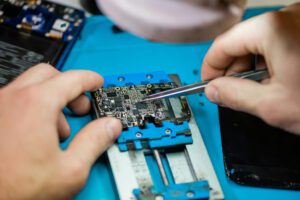 Technician using tweezers to repair a circuit board on a workbench