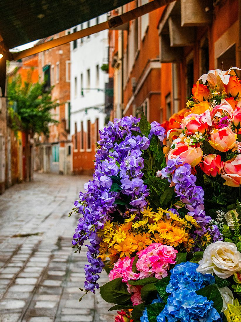 Colorful bouquet of flowers displayed on a street with historic European buildings in the background